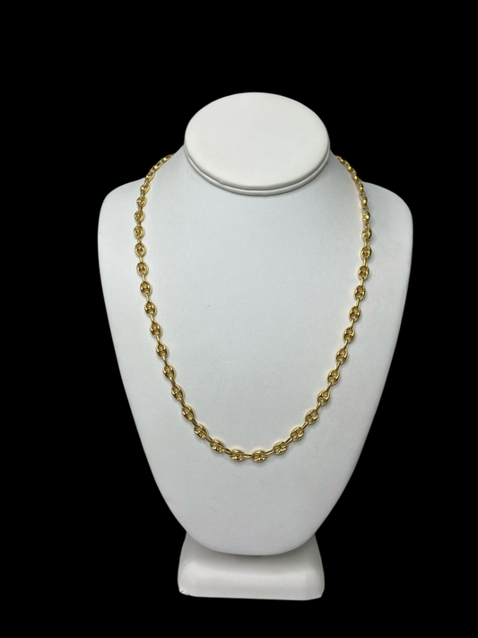 Gold necklace on a white mannequin bust against a black background